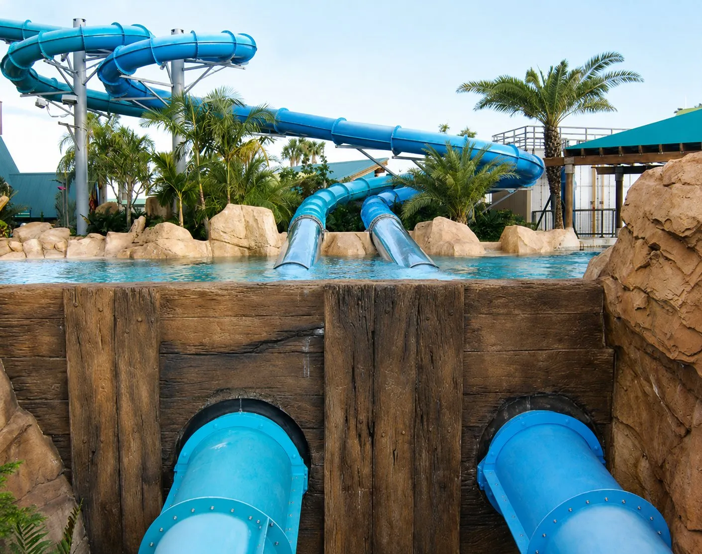 Waterslide flumes discharging into a catch pool with large supply piping below